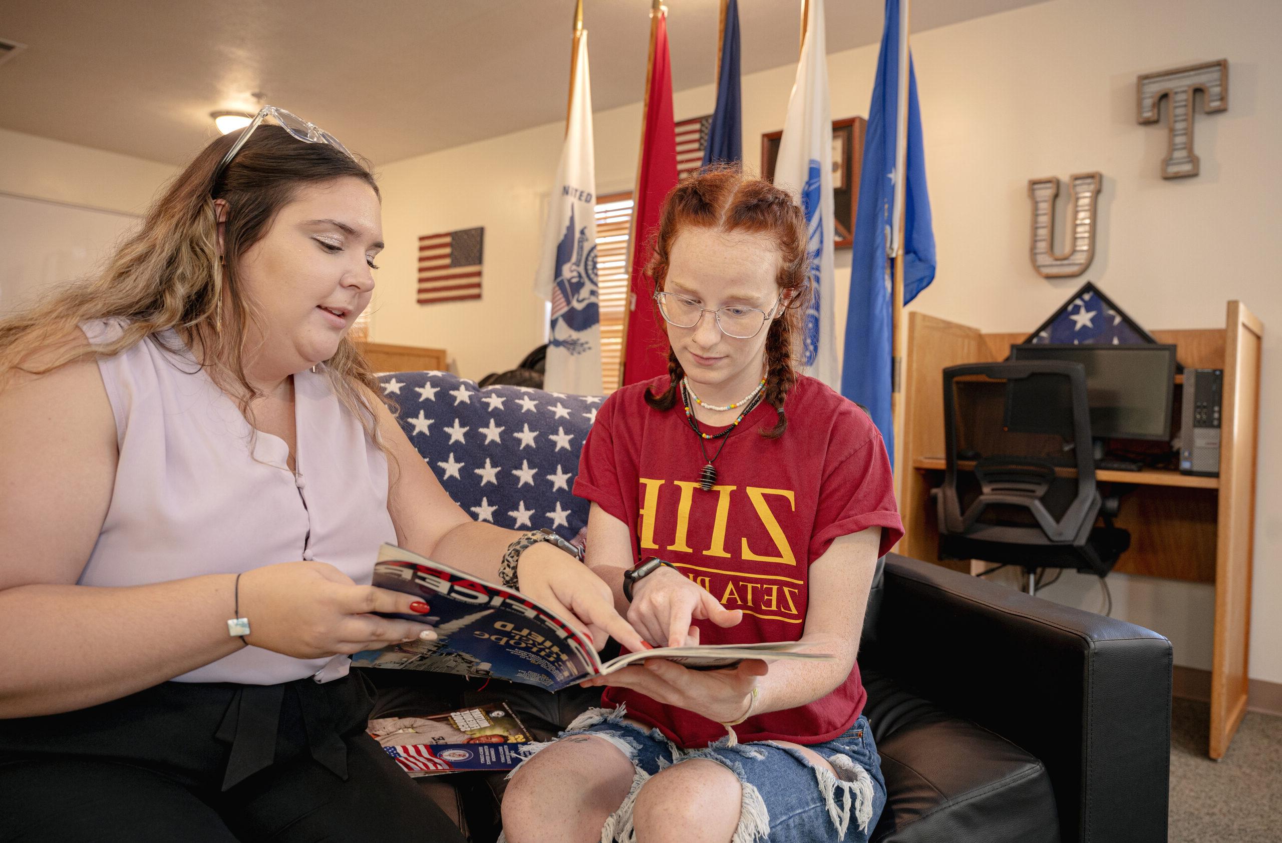 two students in military uniform sitting with an employee